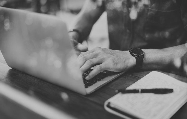 Closeup of man using laptop in cafe grayscale